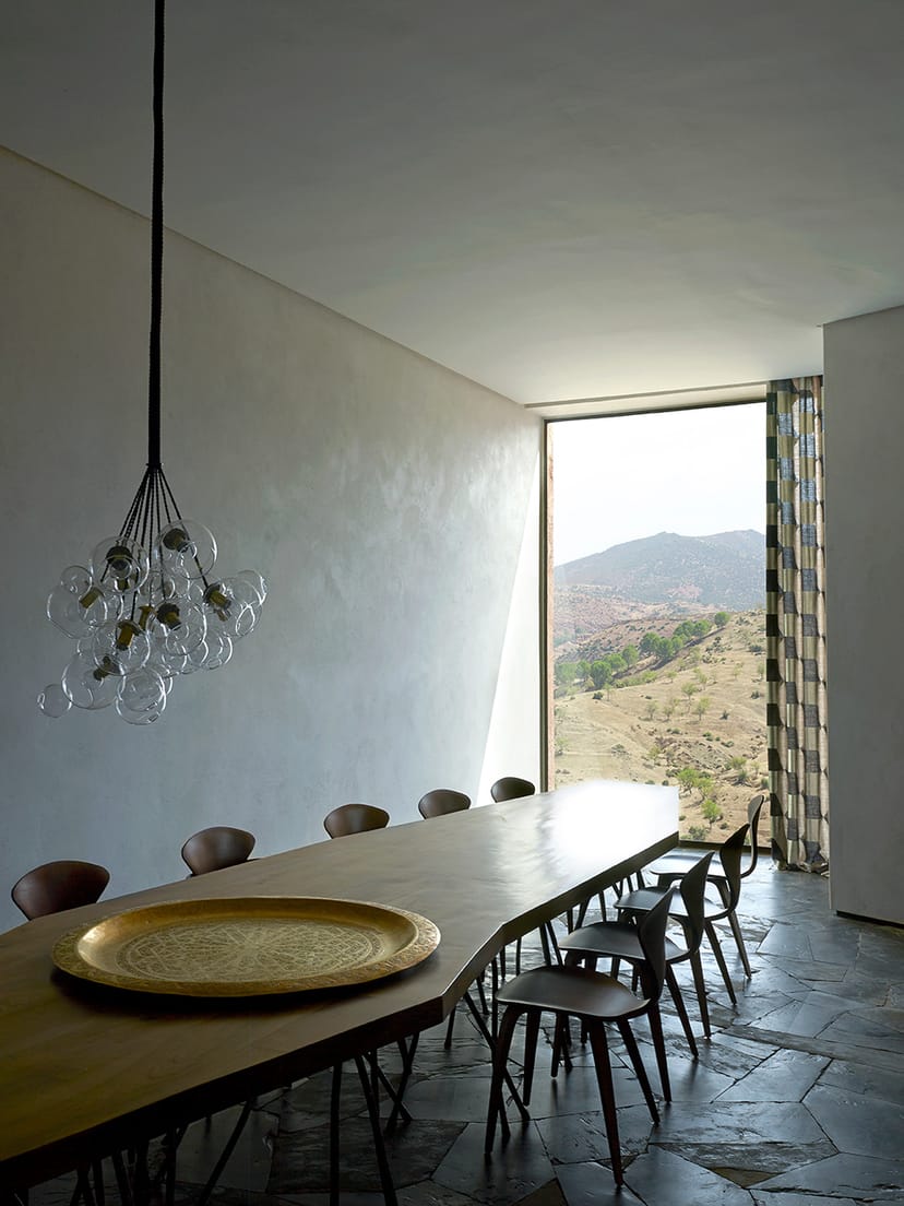 Long wooden dining table under a glass chandelier, Villa E